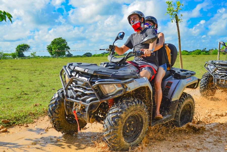 Pareja en ATV doble salpicando lodo por el campo en Punta Cana
