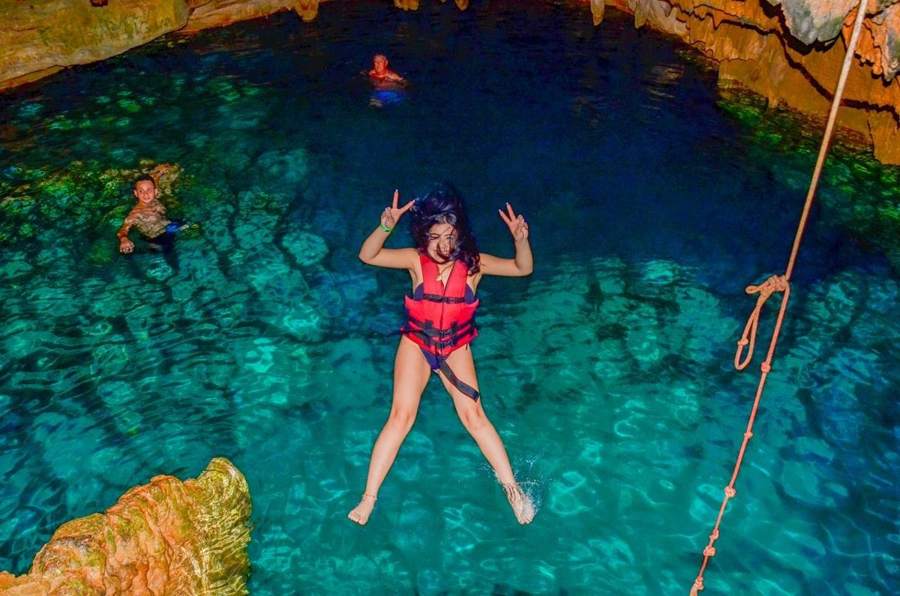 Visitante saltando al agua cristalina de la cueva