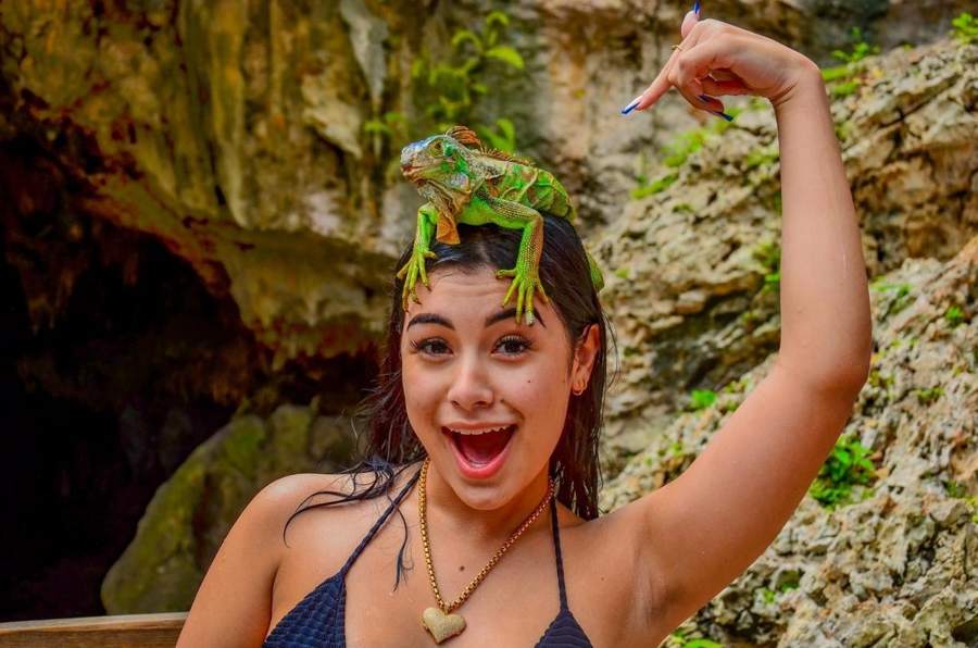 Visitante con una iguana en la cabeza a la entrada de la cueva