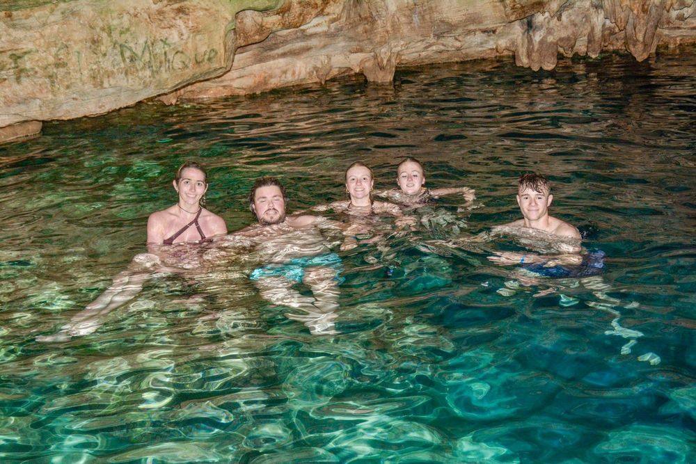 Grupo de visitantes nadando en las aguas turquesa de la cueva