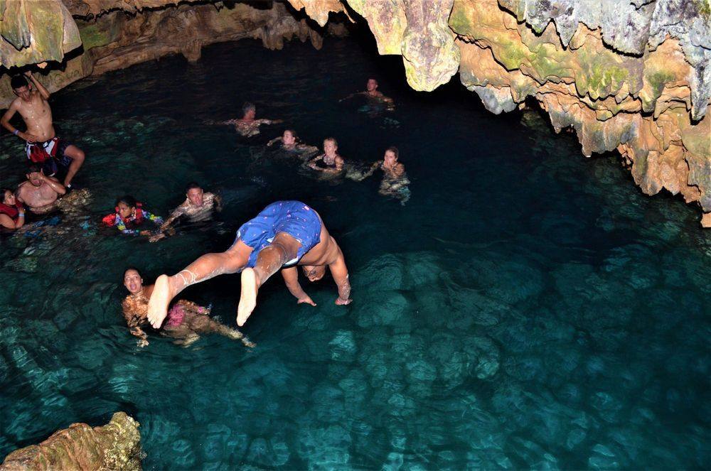 Visitante saltando de cabeza al agua cristalina dentro de la cueva