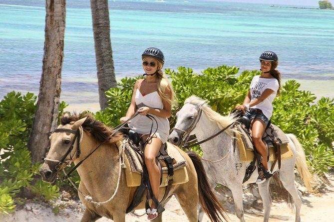 Dos jinetes a caballo junto al mar turquesa