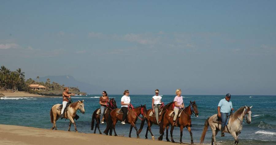 Grupo cabalgando por la orilla del mar en un paseo a caballo