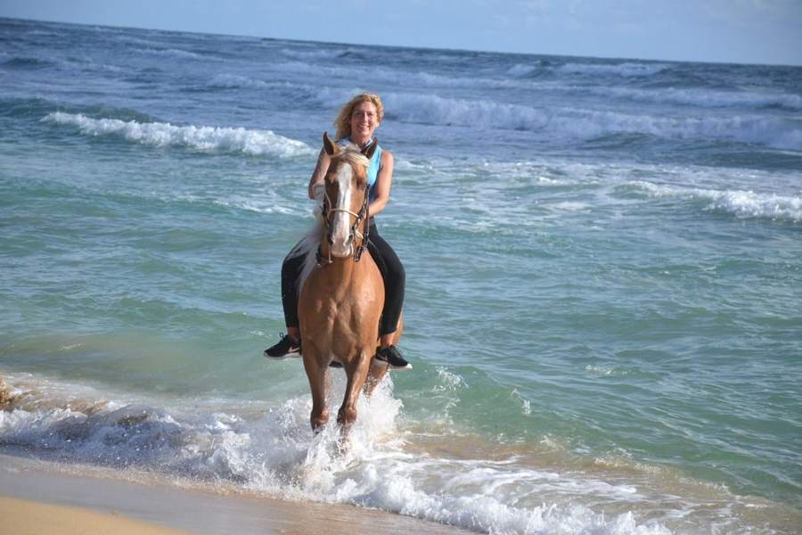 Mujer cabalgando entre las olas en la playa de Uvero Alto