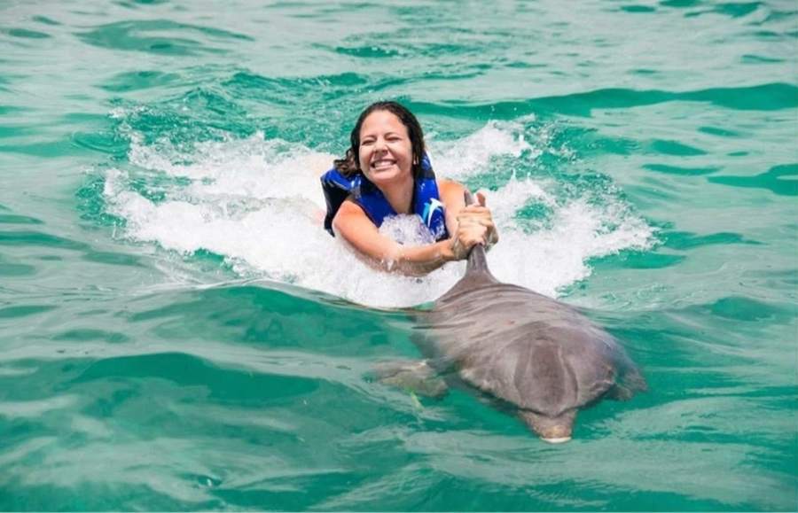 Mujer haciendo el dorsal ride agarrada de la aleta del delfín en Punta Cana