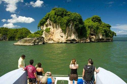 Turistas en catamarán frente a un cayo de Los Haitises con aves