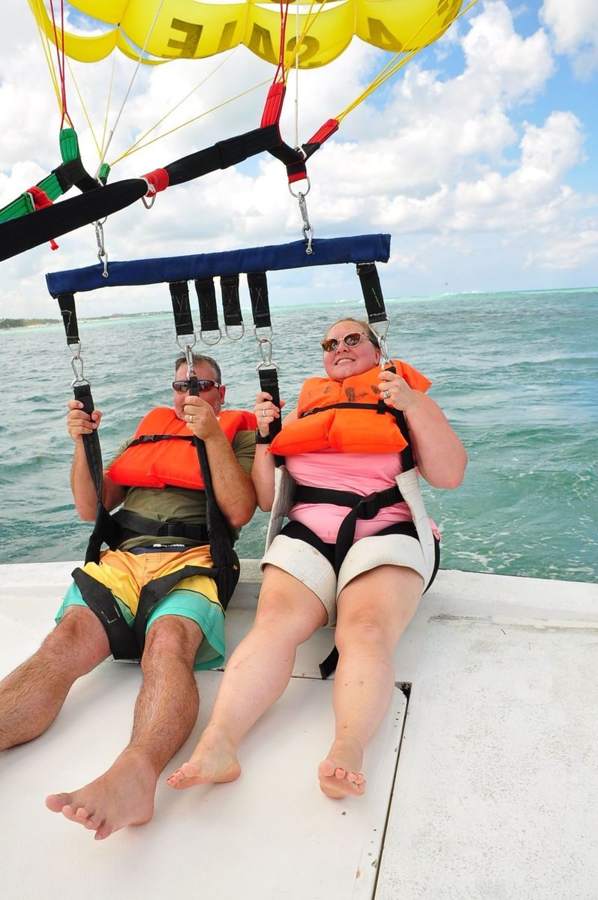 Pareja lista para despegar en parasailing desde la plataforma de la lancha