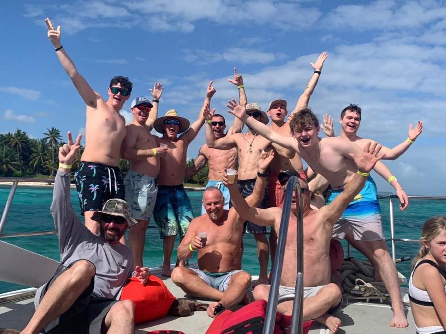 Grupo celebrando en la proa del catamarán con la costa de Punta Cana al fondo